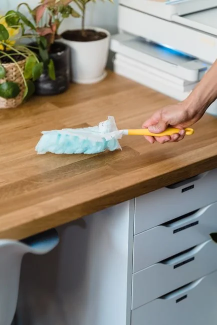 services-03 a-woman-in-a-green-shirt-and-black-gloves-vacuuming-a-gray-ottoman-5txz228u4eo